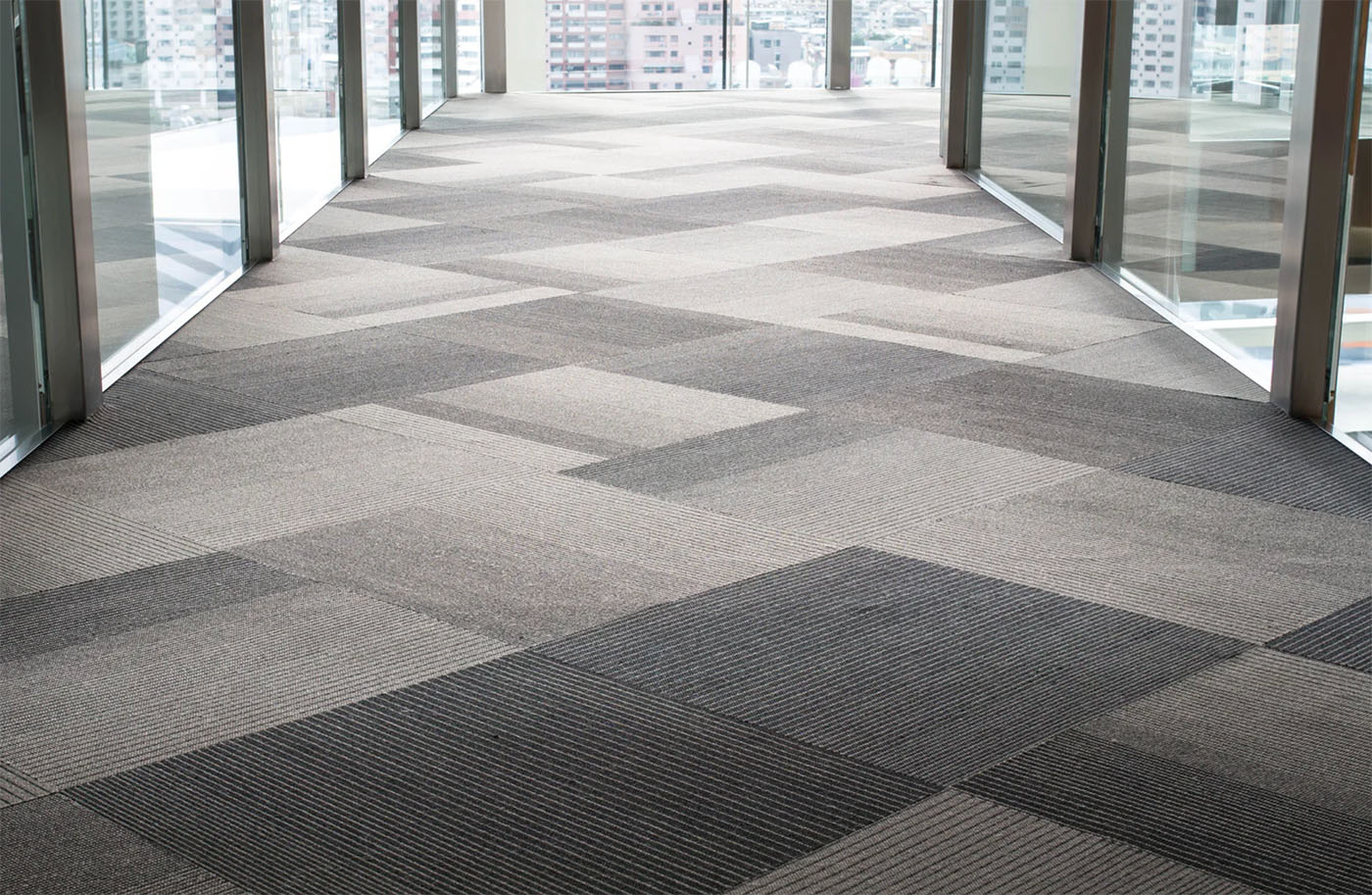 Couloir de bureaux moderne avec dalles de moquette grises posées par jordan harkat à montauban