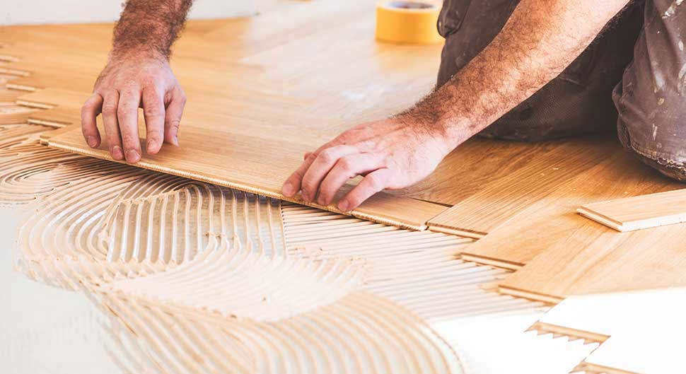 Pose minutieuse de parquet bois clair par jordan harkat à montauban, mains ajustant une lame sur colle striée